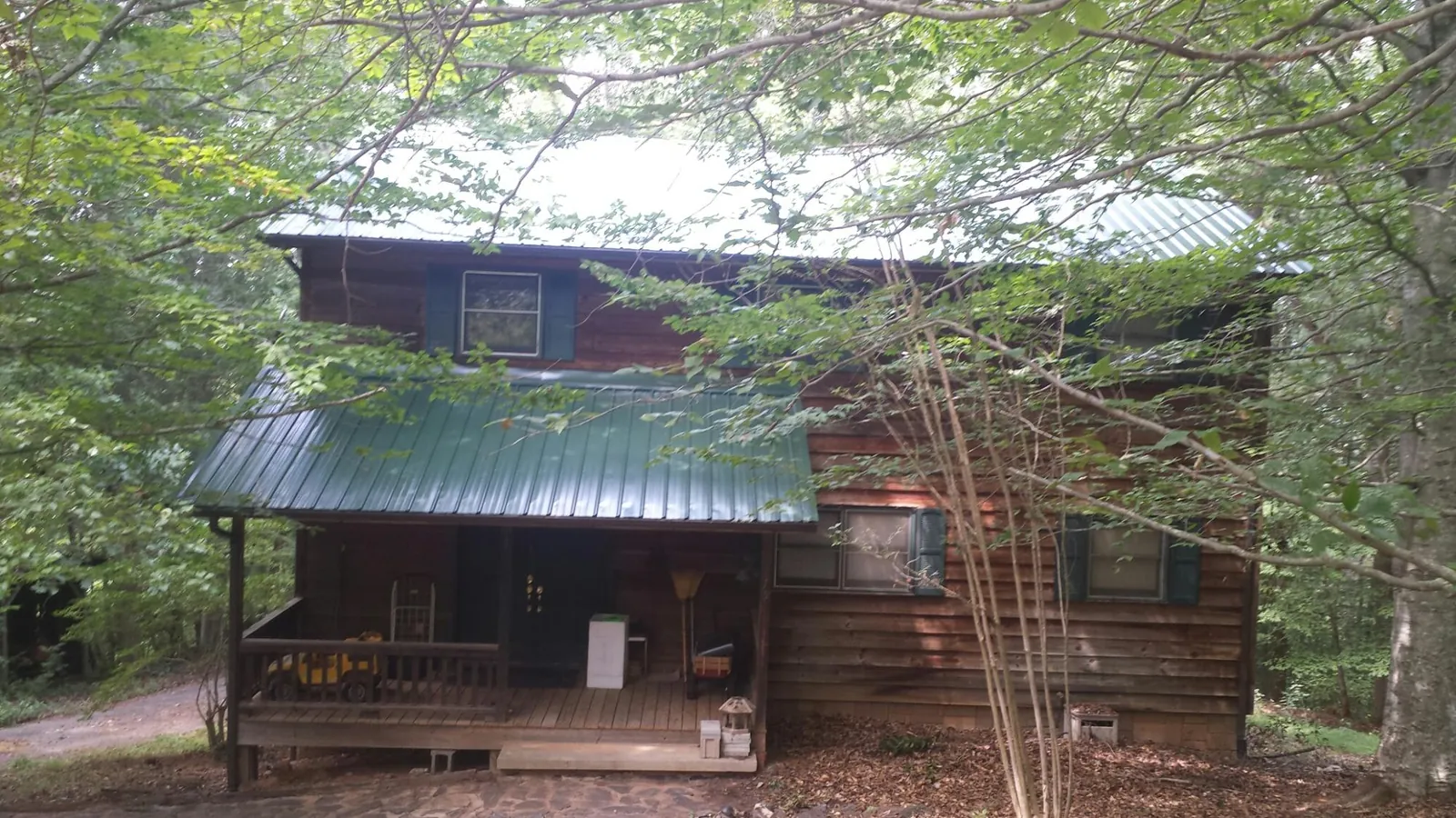 Green metal roof and covered porch on a log cabin in Redwood City