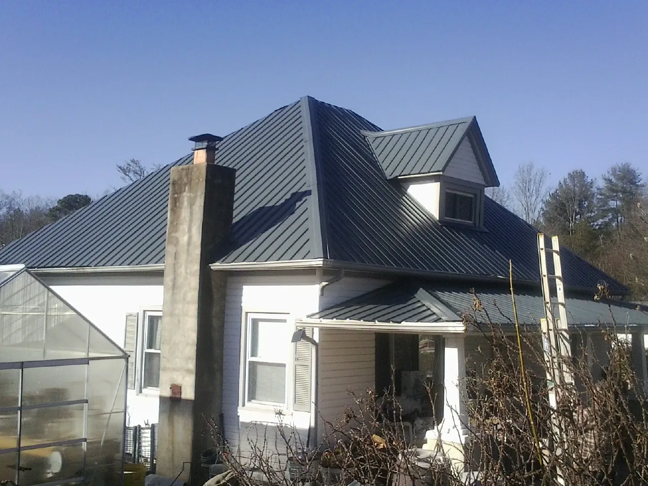 Dark blue standing seam metal roof on a white farmhouse with dormer — Slate & Tile Roof Repair by Roofing Brothers in Redwood City