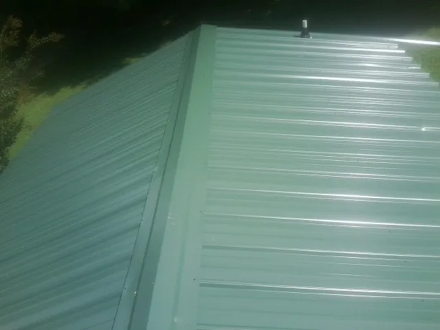 New green metal panels meeting at the ridge of a roof — Flat Roof Repair work by our crew in Redwood City