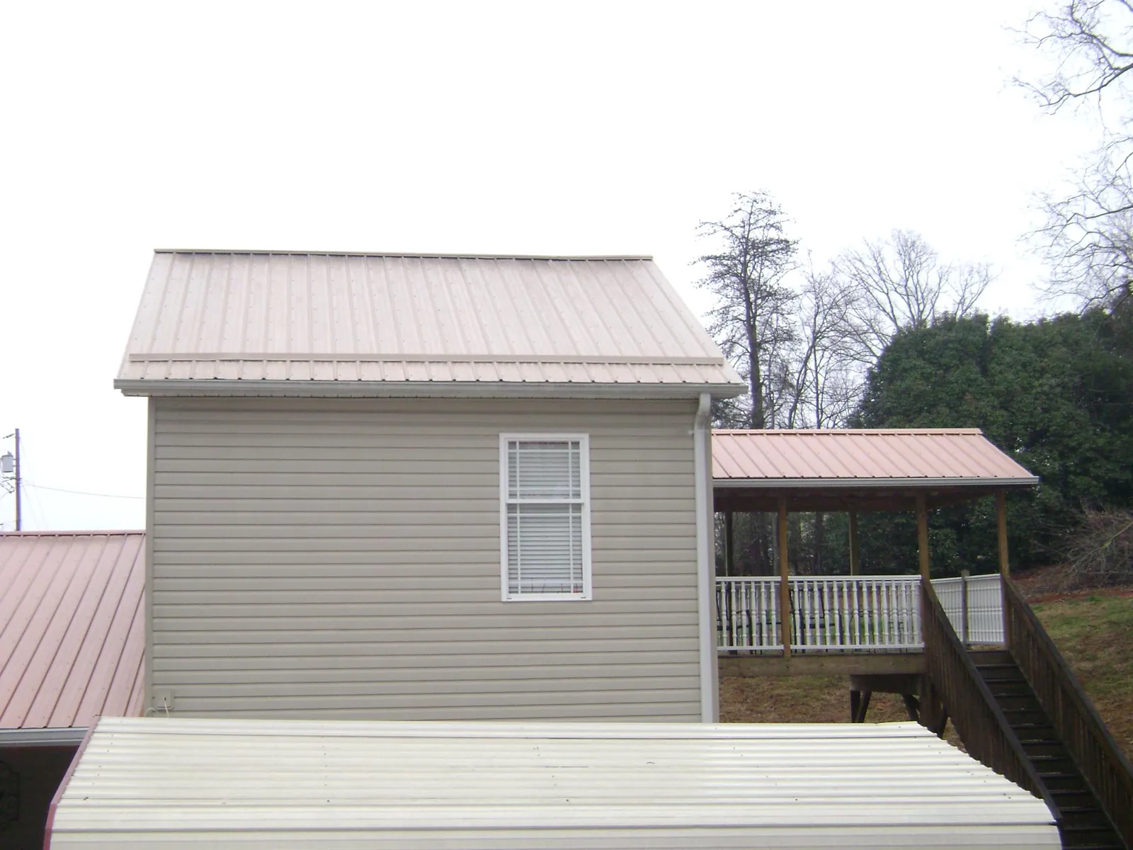 Tan metal roofs on a two story addition and attached porch, from a Roof Replacement job in Redwood City
