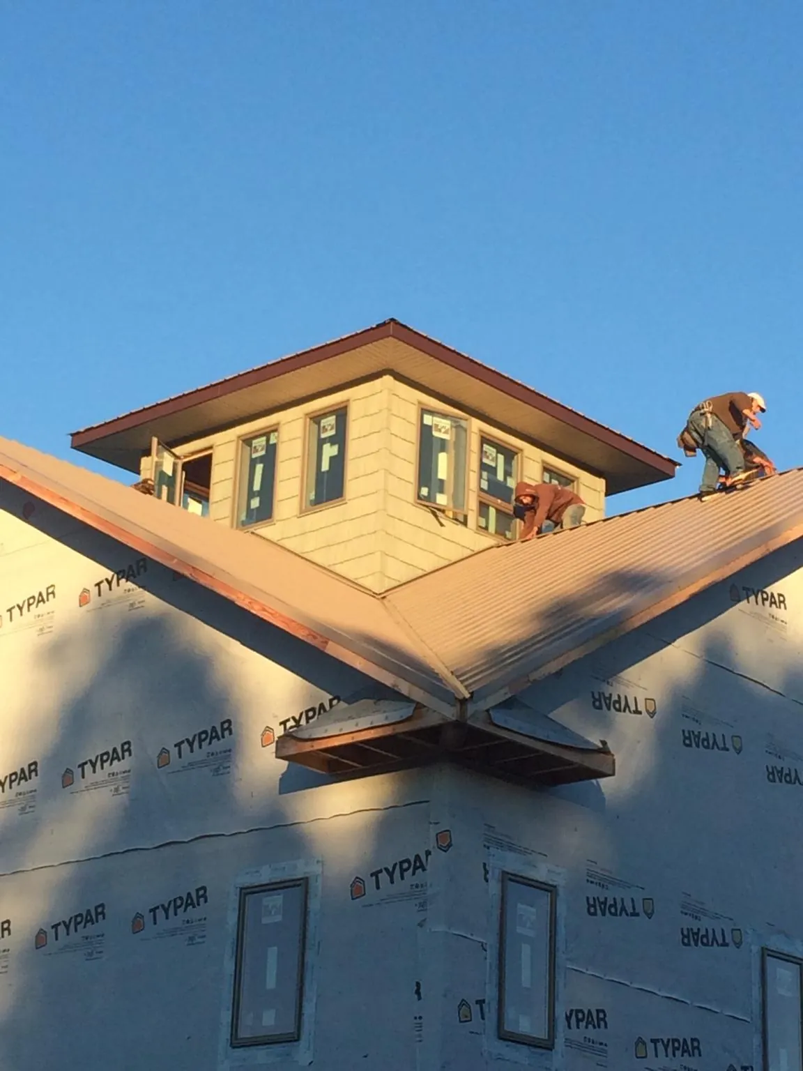 Roofers working around a rooftop cupola on a new metal roof at sunset — Roof Waterproofing in Redwood City by Roofing Brothers
